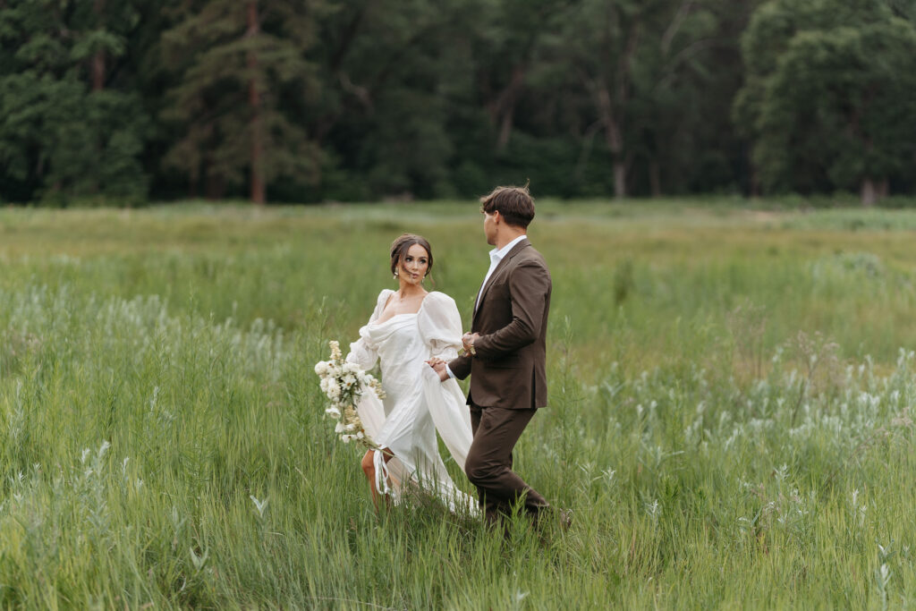 Scenic view of couple surrounded by tall grass and forest backdrop