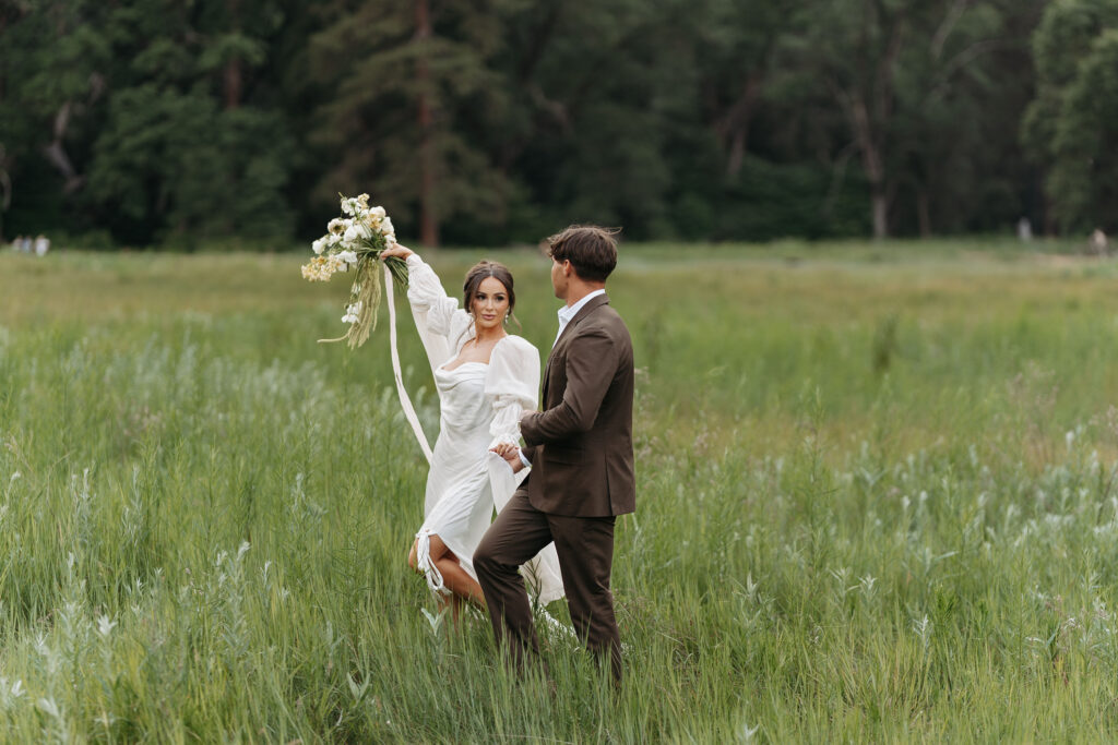 Scenic view of couple surrounded by tall grass and forest backdrop