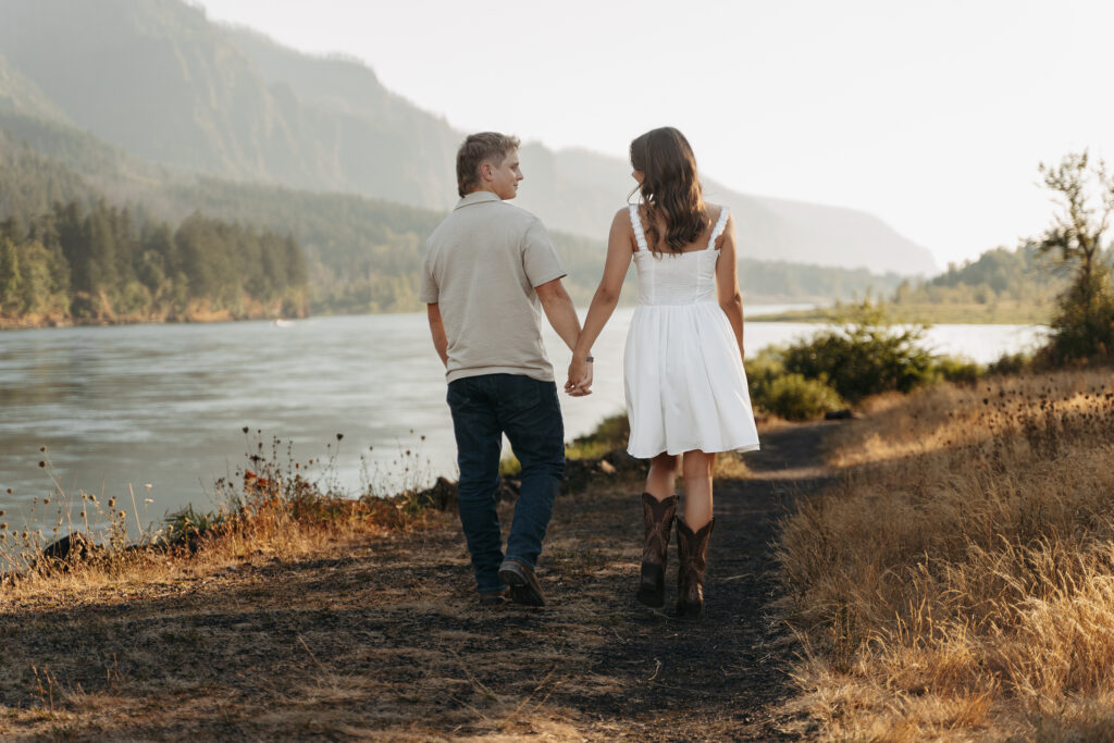 Bride-to-be in white sundress and cowboy boots with fiancé at golden hour