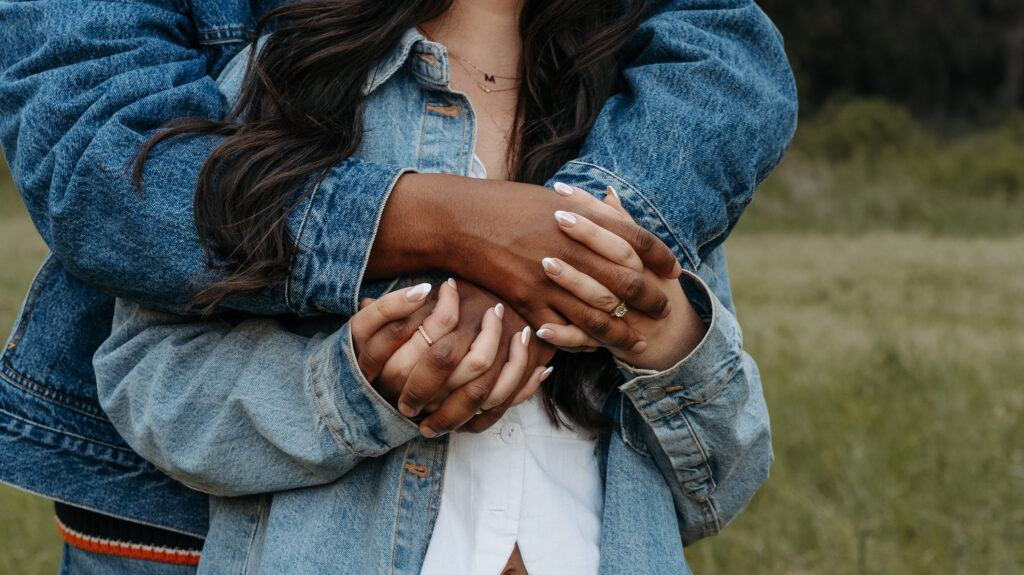 Close up photo of couple holding hands in matching denim outfits