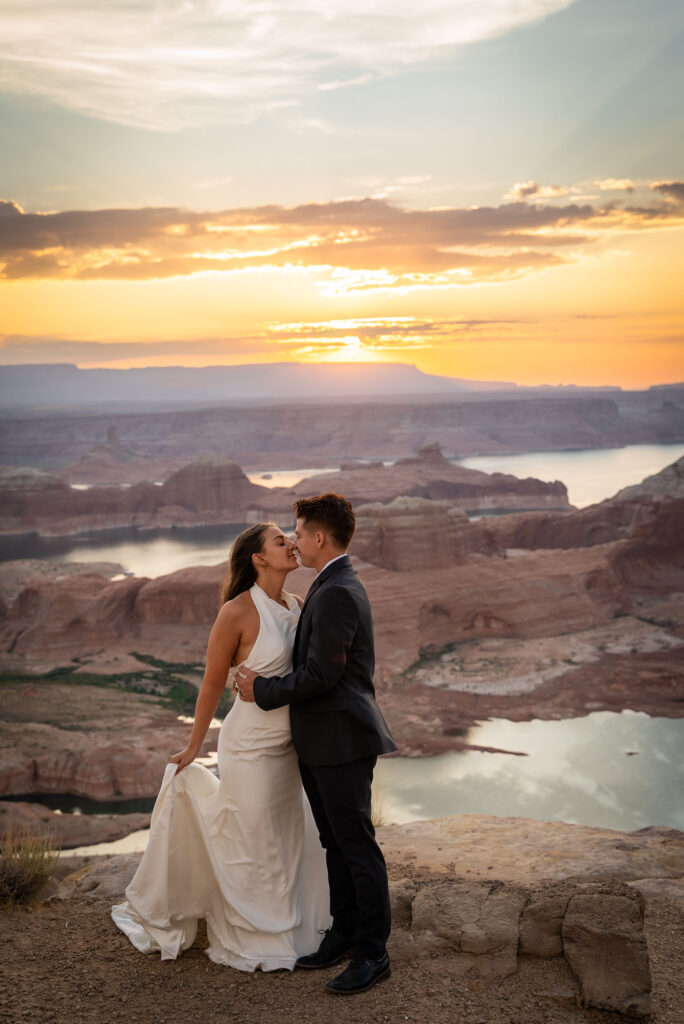Couple embracing on the cliffs of Alstrom Point at golden hour overlooking Lake Powell.