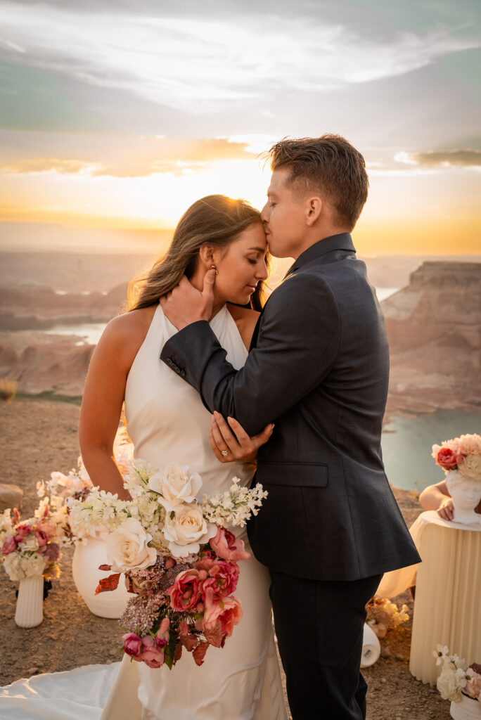 Romantic kiss as the sky turns shades of pink and orange at sunset.