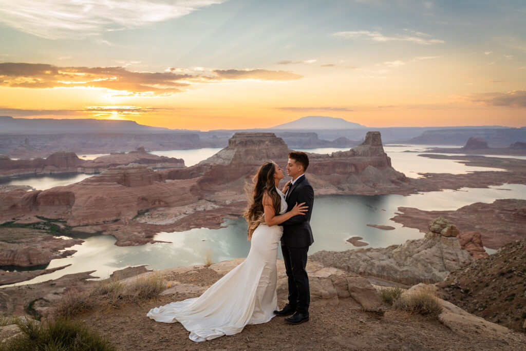Couple standing on desert cliffs, framed by glowing orange skies.