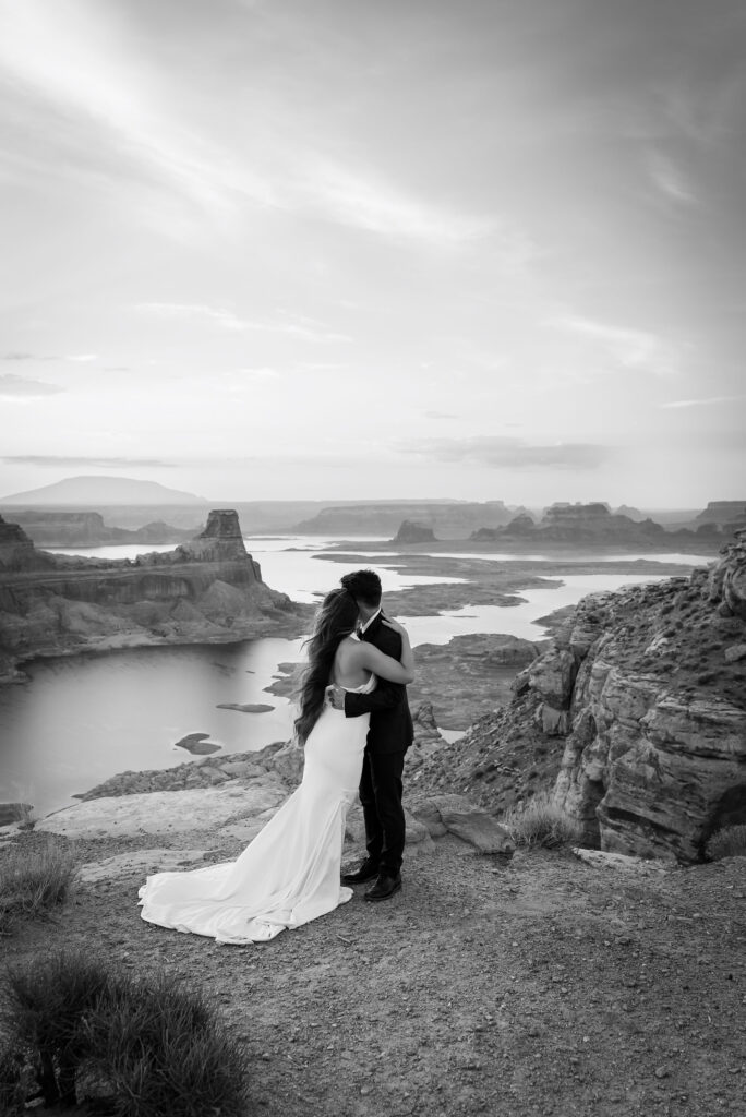 Black and white shot of couple embracing against dramatic cliff edges.