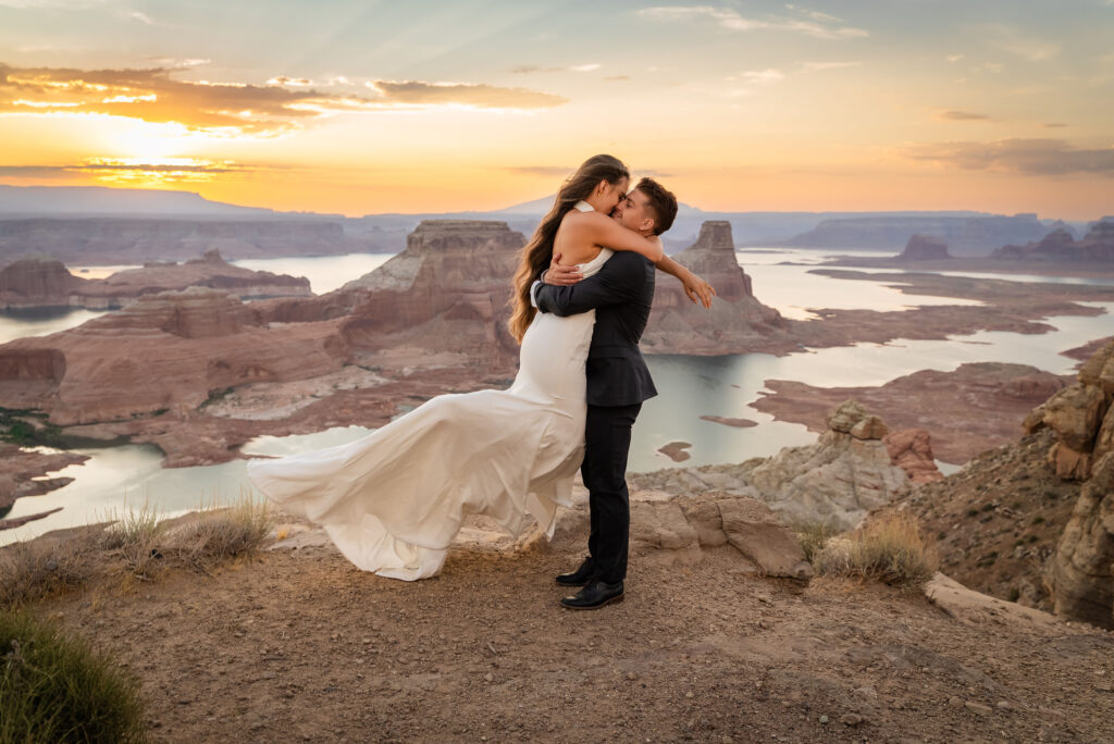 Groom lifting bride as the sun sets over Lake Powell.