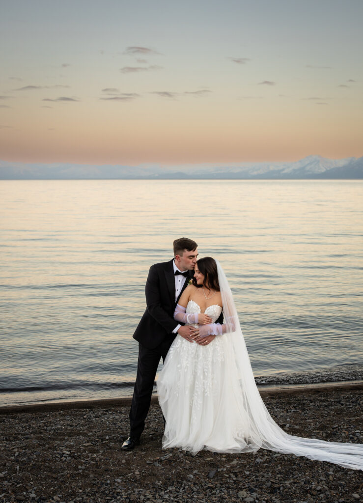 Groom kissing bride by the water