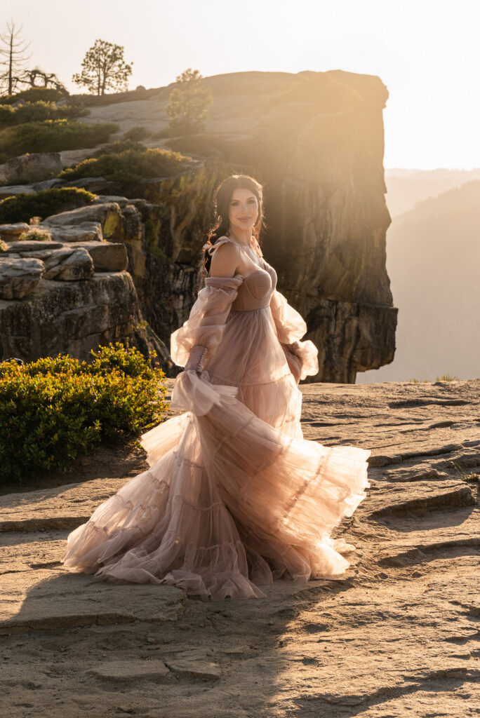 Bride in a flowing chiffon dress standing gracefully by the cliffs at sunset