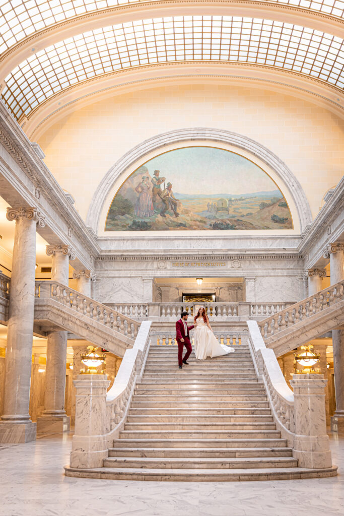 Couple standing on the staircase surrounded by soft light — elegant indoor Utah State Capitol formal session.