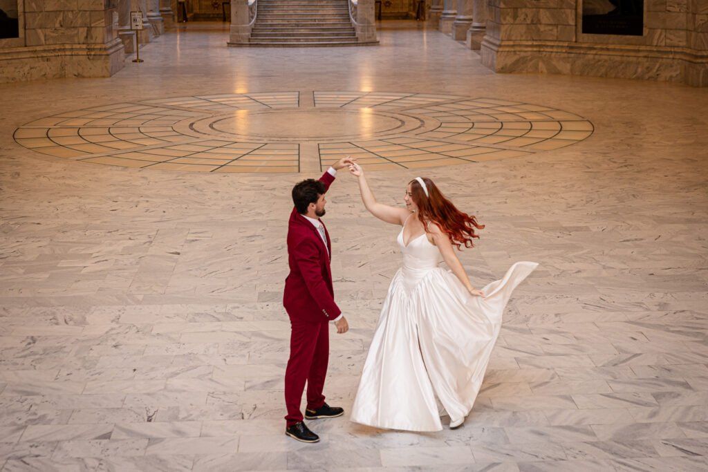 Bride laughing as the groom twirls her inside the marble halls of the Utah State Capitol — romantic Salt Lake City elopement.