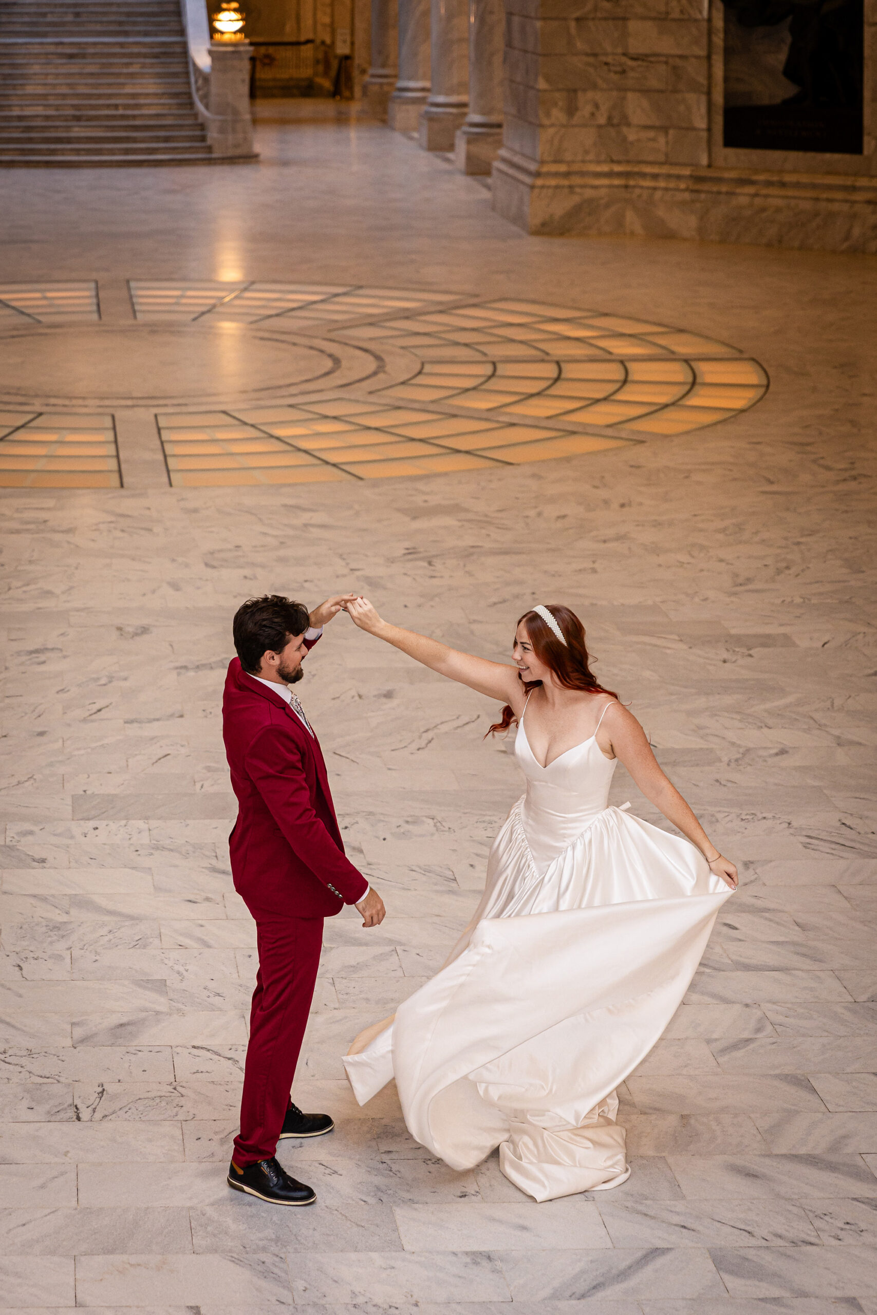 Full-body indoor shot of the couple surrounded by marble columns at the Salt Lake City Capitol.