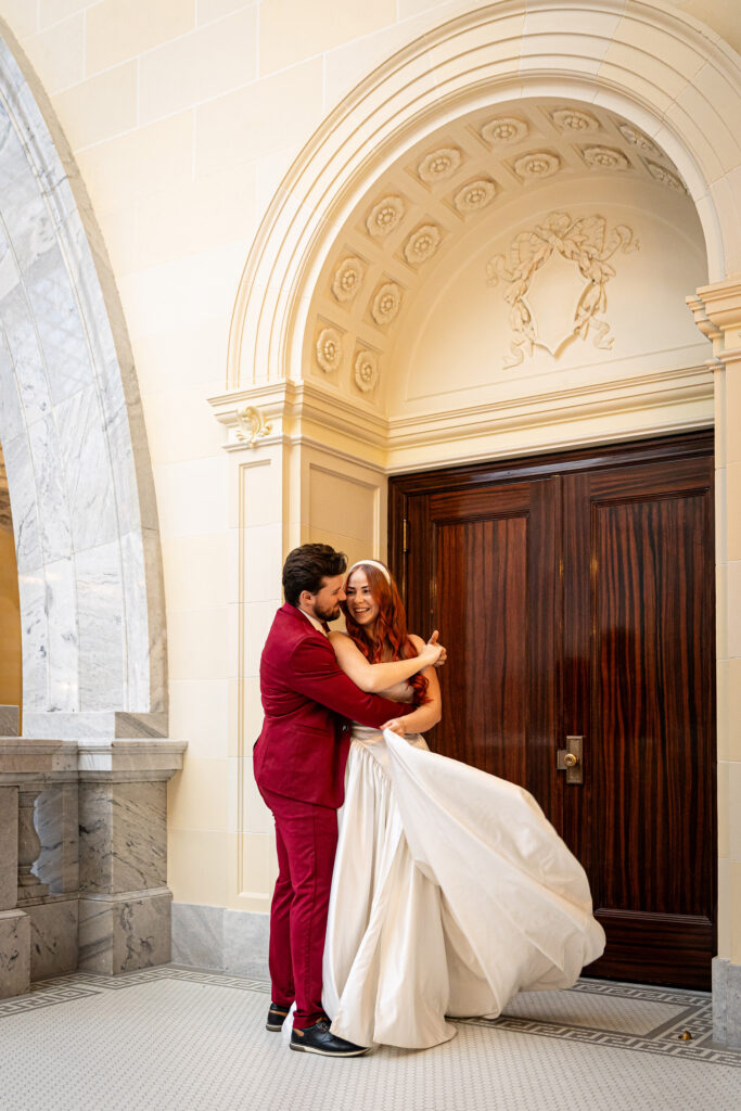 Couple embracing in front of the Utah State Capitol columns — cinematic outdoor formal session in golden light.