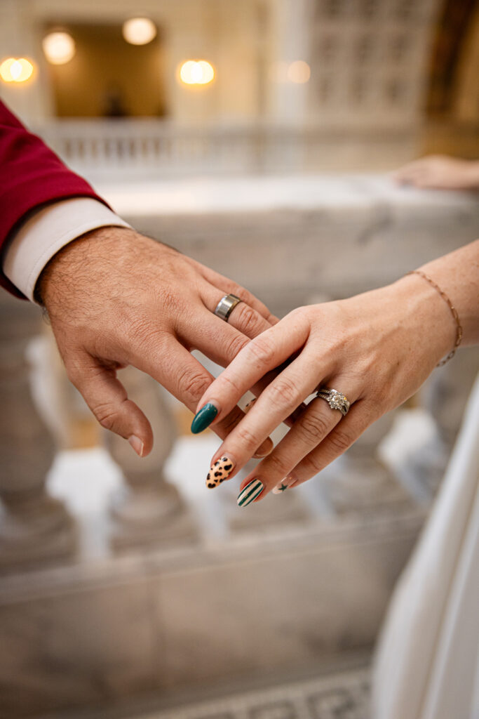 Close-up of couple’s hands wearing wedding rings during their Utah State Capitol courthouse elopement.
