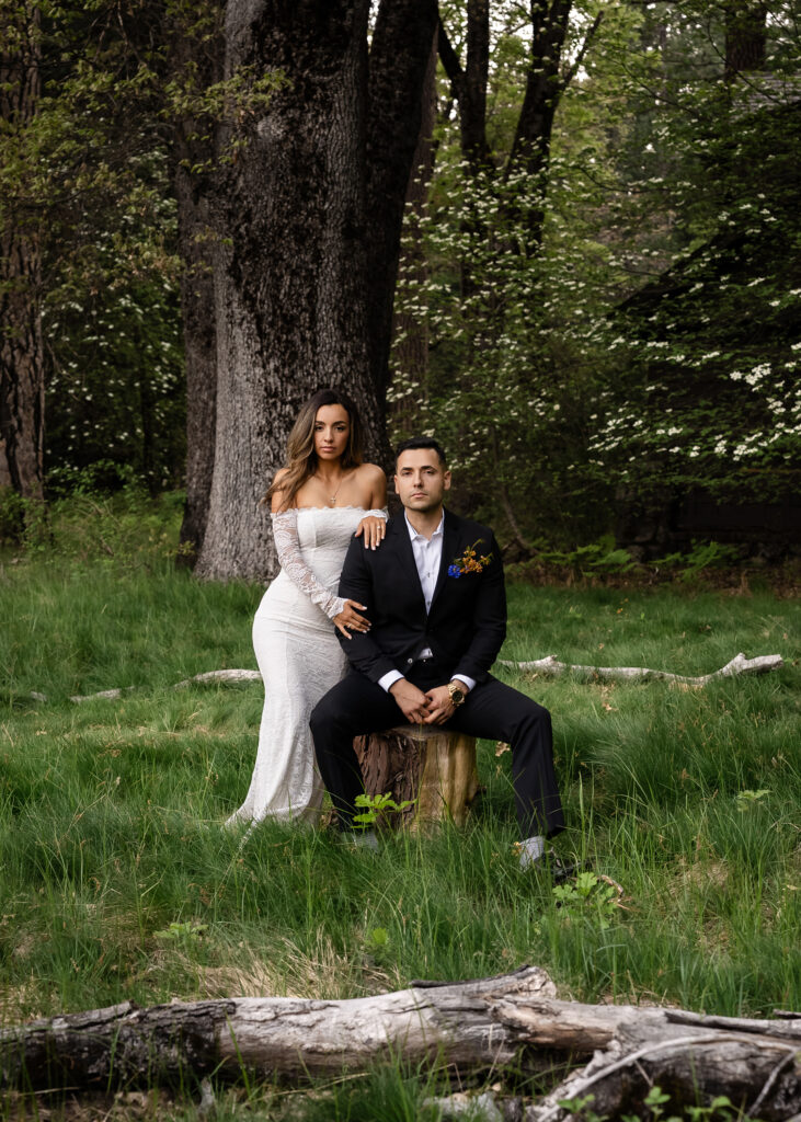 Bride and groom sitting together in a quiet forest surrounded by tall trees